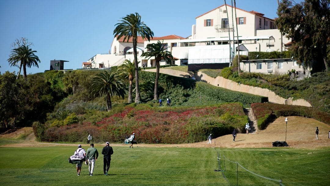 Players and caddies walk back to the clubhouse from the first hole after wind suspended play during the third round of the Genesis Invitational golf tournament at Riviera Country Club.