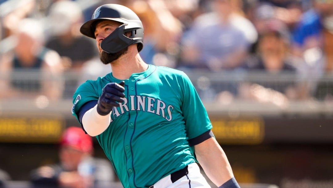 Seattle Mariners designated hitter Mitch Haniger, left, follows through on a home run against the Cleveland Guardians during the first inning of a spring training baseball game Sunday, Feb. 25, 2024, in Peoria, Ariz. (AP Photo/Lindsey Wasson)