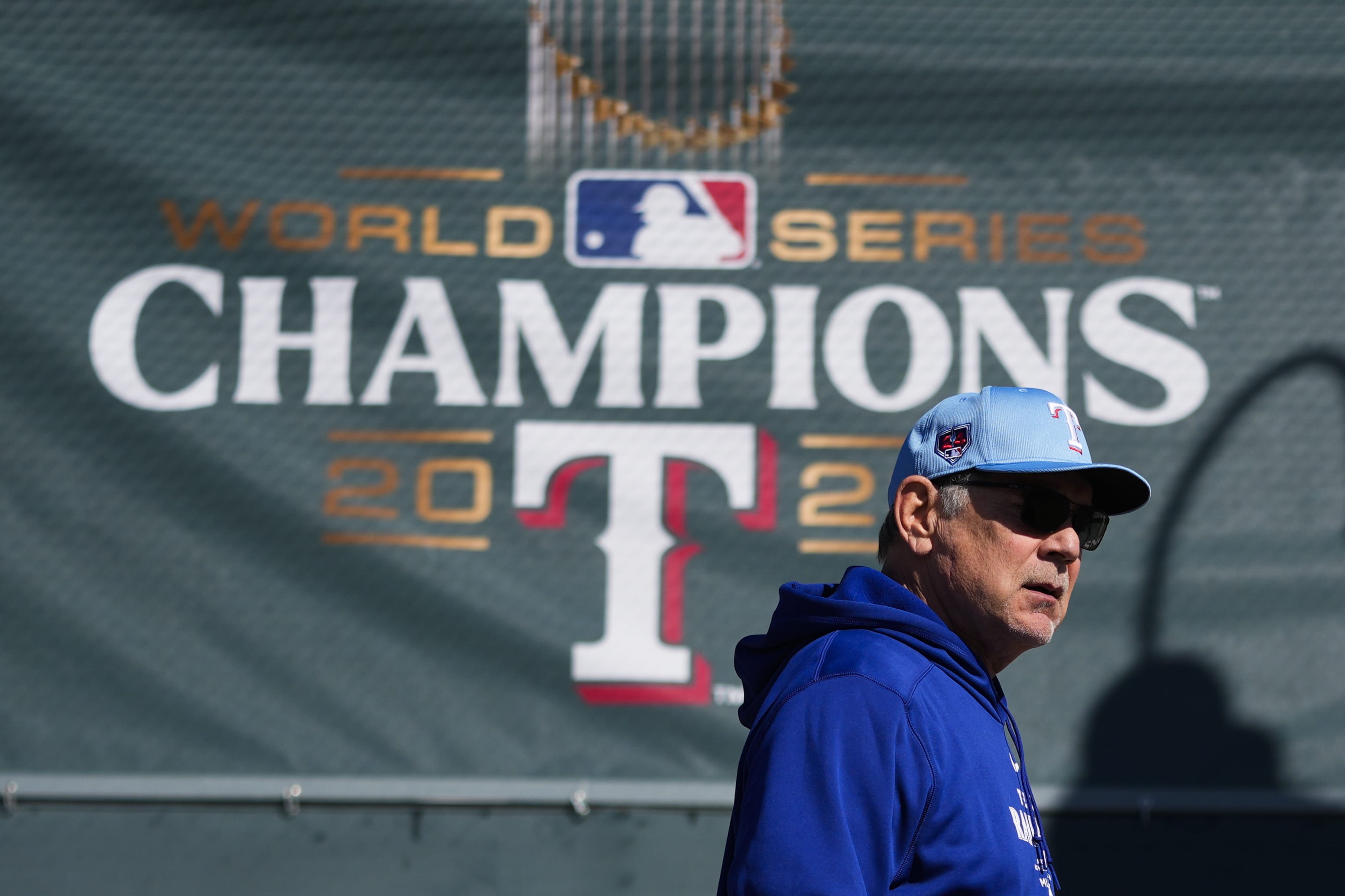 Texas Rangers manager Bruce Bochy walks by a 2023 World Series champions banner before his team's spring training baseball workouts Wednesday, Feb. 14, 2024, in Surprise, Ariz.