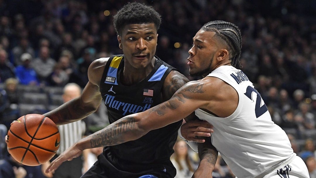 Xavier guard Dayvion McKnight (20) attempts to tip the ball away from Marquette guard Kam Jones (1) during the second half of an NCAA college basketball game in Cincinnati, Saturday, March 9, 2024. Marquette won 86-80.