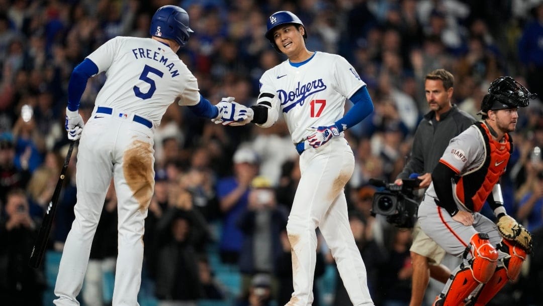 Los Angeles Dodgers designated hitter Shohei Ohtani celebrates with Freddie Freeman (5) after hitting a home run during the seventh inning of a baseball game against the San Francisco Giants in Los Angeles, Wednesday, April 3, 2024.