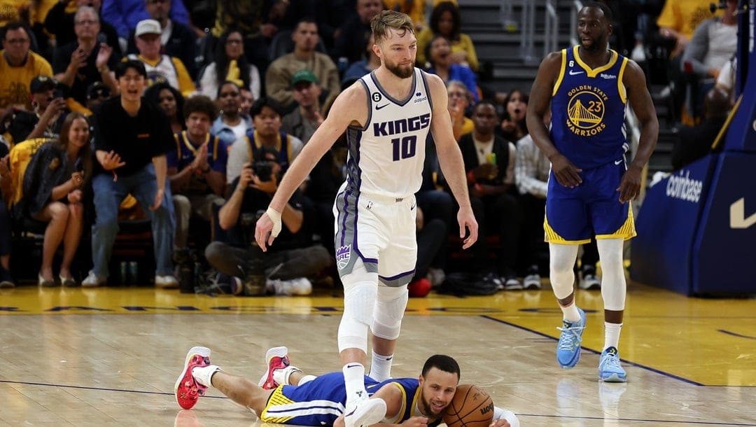 Domantas Sabonis #10 of the Sacramento Kings steps over Stephen Curry #30 of the Golden State Warriors after Sabonis fouled Curry in the second half of Game Six of the Western Conference First Round Playoffs at Chase Center on April 28, 2023 in San Francisco, California.