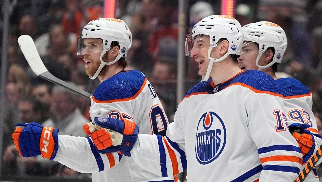 Edmonton Oilers left wing Zach Hyman, center, celebrates his goal with center Connor McDavid, left, and center Ryan Nugent-Hopkins during the third period in Game 3 of an NHL hockey Stanley Cup first-round playoff series against the Los Angeles Kings Friday, April 26, 2024, in Los Angeles. (AP Photo/Mark J. Terrill)