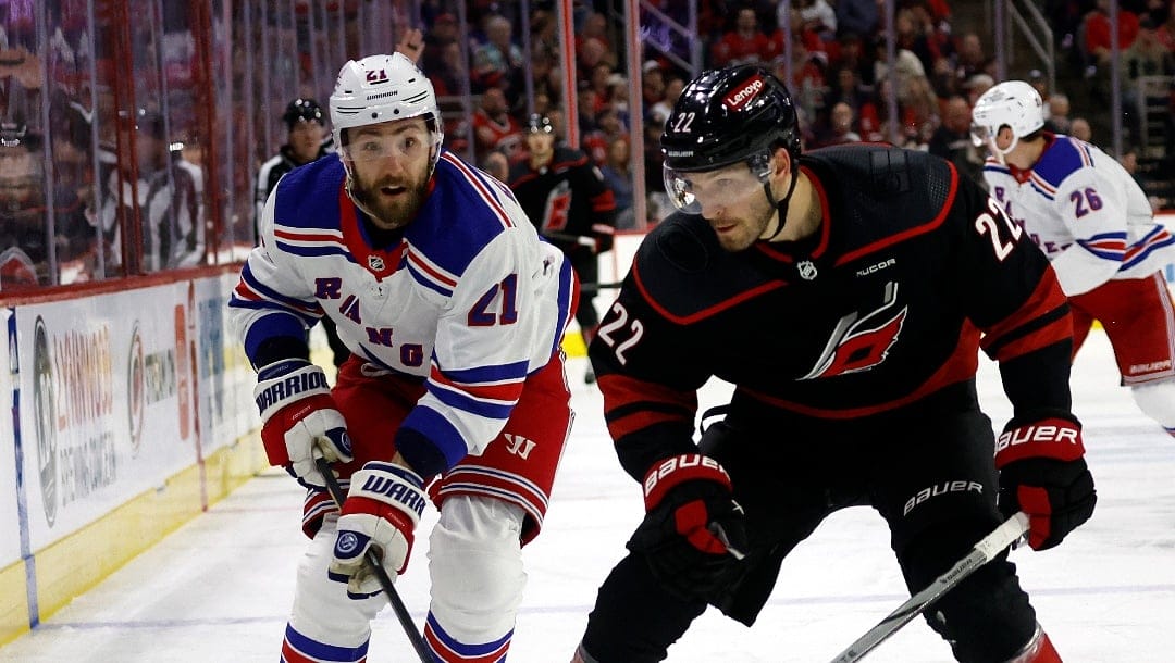 Carolina Hurricanes' Brett Pesce (22) tries to protect the puck from New York Rangers' Barclay Goodrow (21) during the third period of an NHL hockey game in Raleigh, N.C., Tuesday, March 12, 2024. (AP Photo/Karl B DeBlaker)