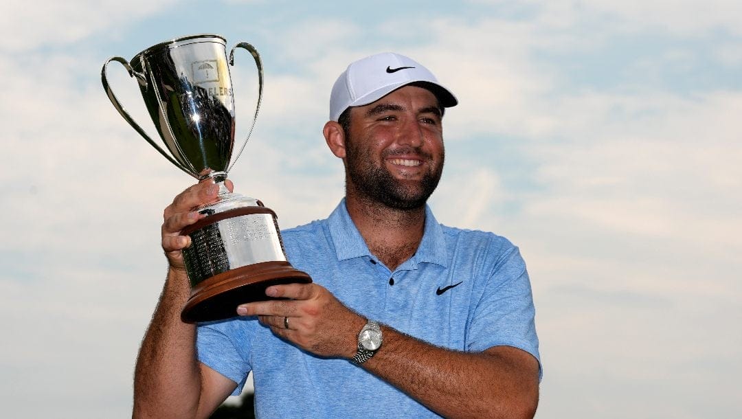 Scottie Scheffler holds up his trophy after winning the Travelers Championship golf tournament at TPC River Highlands, Sunday, June 23, 2024, in Cromwell, Conn.