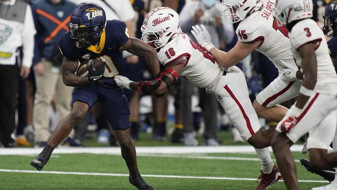 Toledo running back Jacquez Stuart (0) pulls away from Miami (Ohio) defensive back Eli Blakey (16) during the first half of the Mid-American Conference championship NCAA college football game, Saturday, Dec. 2, 2023, in Detroit.