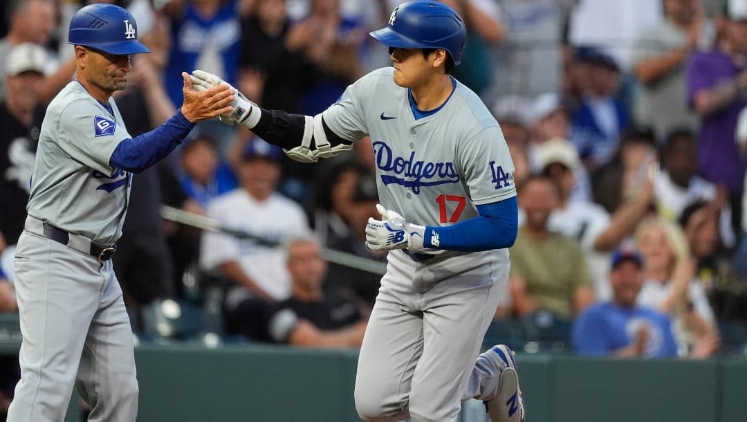 Los Angeles Dodgers third base coach Dino Ebel, left, congratulates Shohei Ohtani for a solo home run off Colorado Rockies starting pitcher Austin Gomber during the sixth inning of a baseball game Tuesday, June 18, 2024, in Denver.