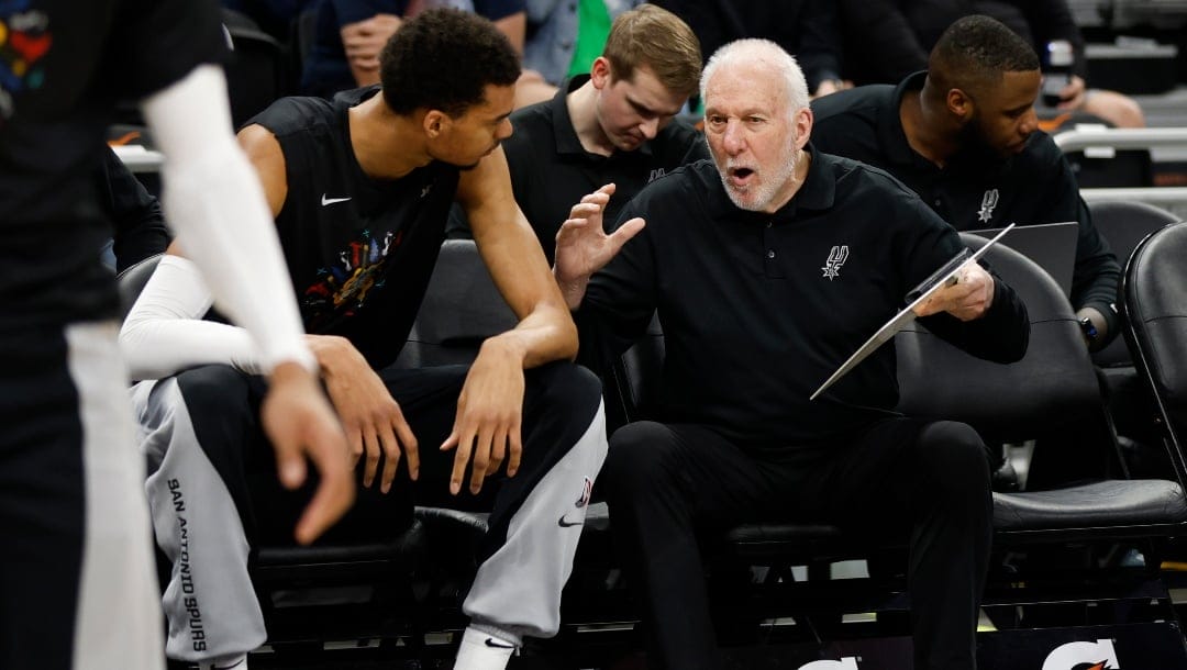 Victor Wembanyama #1 and head coach Gregg Popovich of the San Antonio Spurs talk before a game against the Brooklyn Nets at Moody Center on March 17, 2024 in San Antonio, Texas.