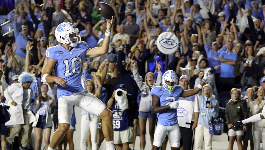 North Carolina quarterback Drake Maye (10) flips the ball into the air after scoring a rushing touchdown as teammate wide receiver Gavin Blackwell (2) look on during the second overtime of an NCAA college football game against Appalachian State, Saturday, Sept. 9, 2023, in Chapel Hill, N.C.