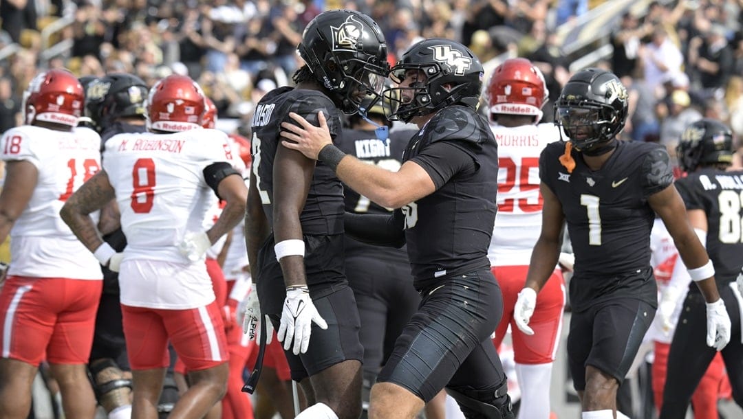 Central Florida quarterback John Rhys Plumlee, center, celebrates his 8-yard rushing touchdown with wide receiver Kobe Hudson (2), left, during the first half of an NCAA college football game against Houston, Saturday, Nov. 25, 2023, in Orlando, Fla.