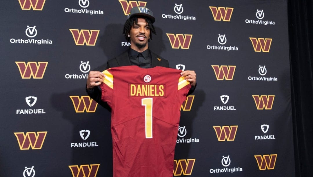 Washington Commanders' first round draft pick Jayden Daniels holds his Commanders jersey during an NFL football news conference in Ashburn, Va., Friday, April 26, 2024.