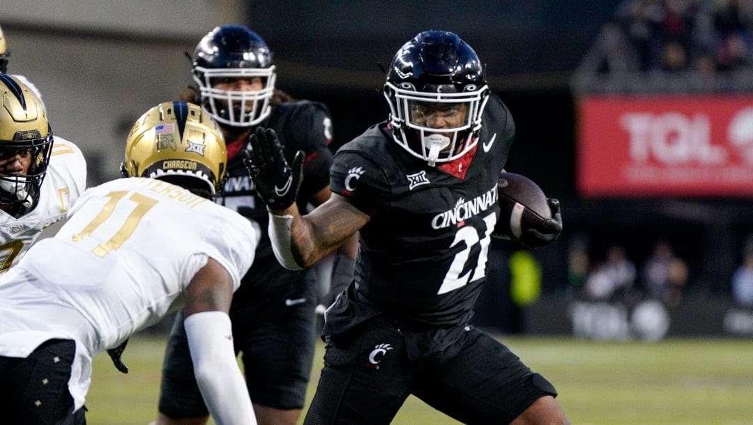 Cincinnati running back Corey Kiner (21) scores against Central Florida defensive back Decorian Patterson (11) during the second half of an NCAA college football game, Saturday, Nov. 4, 2023, in Cincinnati. (AP Photo/Jeff Dean)