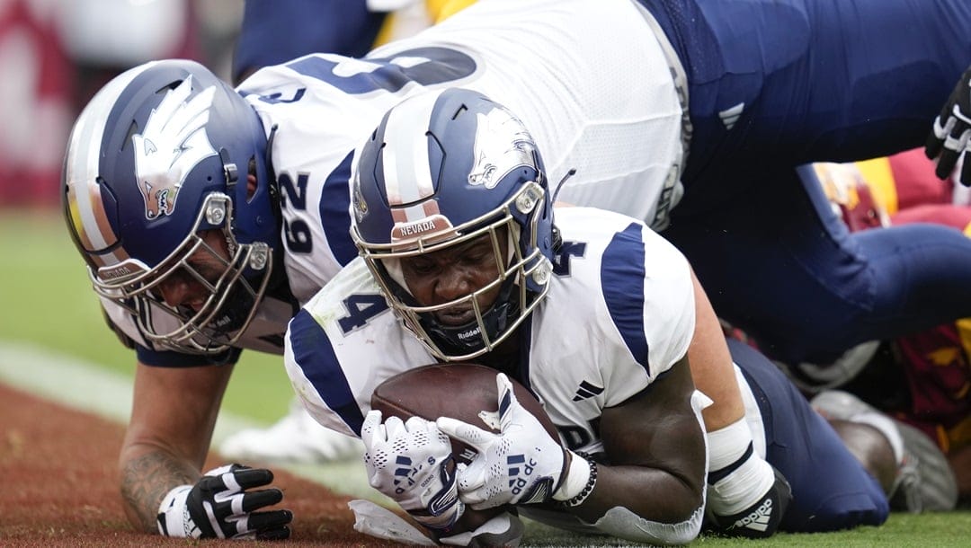 Nevada running back Sean Dollars (4) scores a touchdown as offensive lineman Frank Poso (62) falls on top of him during the first half of an NCAA college football game against Southern California in Los Angeles, Saturday, Sept. 2, 2023.