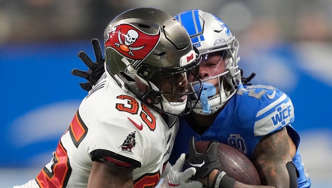 Tampa Bay Buccaneers cornerback Jamel Dean, left, makes a hit on Detroit Lions running back Jahmyr Gibbs during the second half of an NFL football NFC divisional playoff game, Sunday, Jan. 21, 2024, in Detroit. (AP Photo/Carlos Osorio)