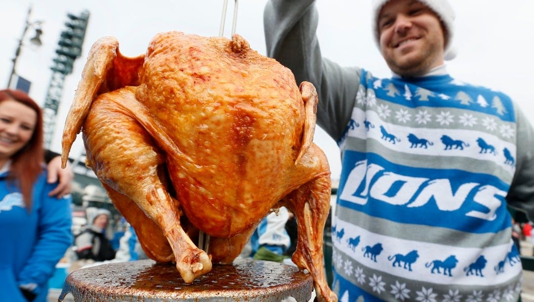 Brent Clodgio checks a Thanksgiving turkey while tailgating before an NFL football game between the Detroit Lions and Chicago Bears in Detroit Thursday, Nov. 27, 2014. (AP Photo/Paul Sancya)