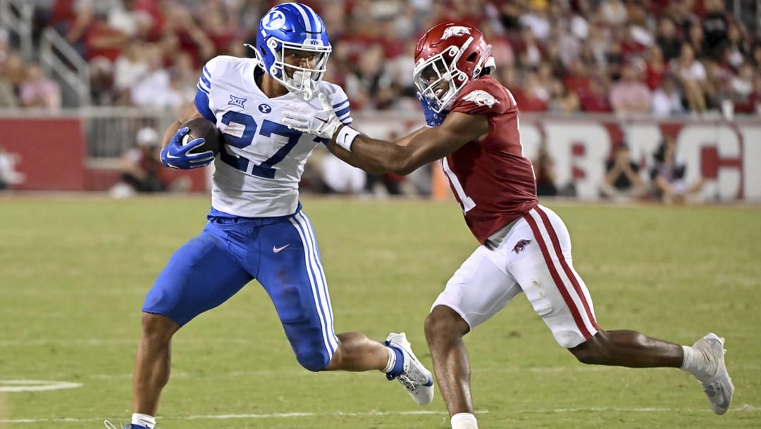 BYU running back LJ Martin (27) tries to get past Arkansas defensive back Jaylon Braxton (11) during an NCAA college football game, Sept. 16, 2023, in Fayetteville, Ark.