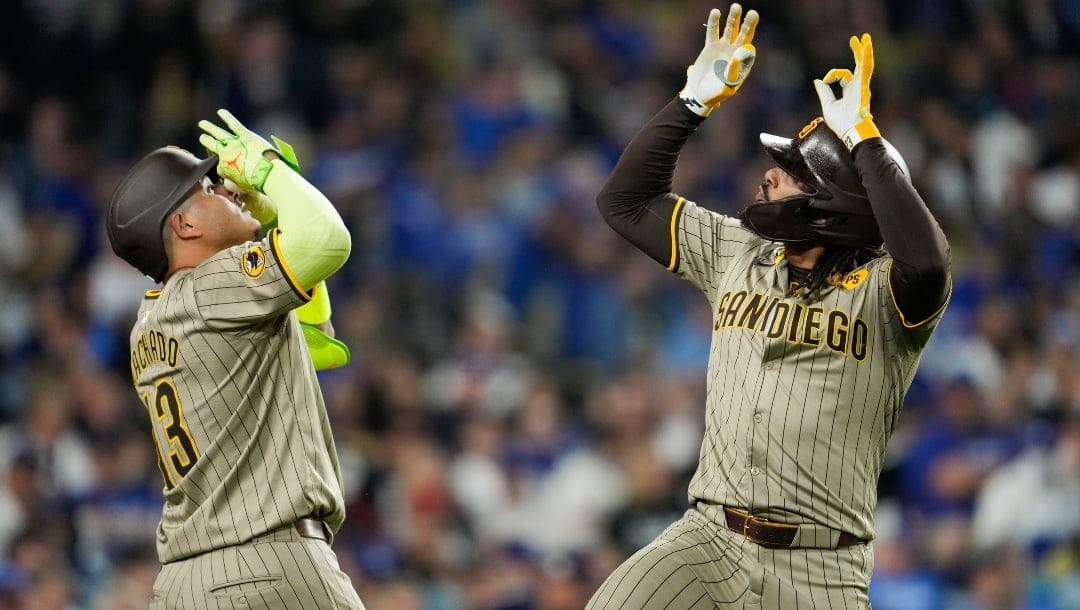 San Diego Padres' Fernando Tatis Jr., right, celebrates with Manny Machado (13) after hitting a home run during the fifth inning of a baseball game against the Los Angeles Dodgers in Los Angeles, Wednesday, Sept. 25, 2024.