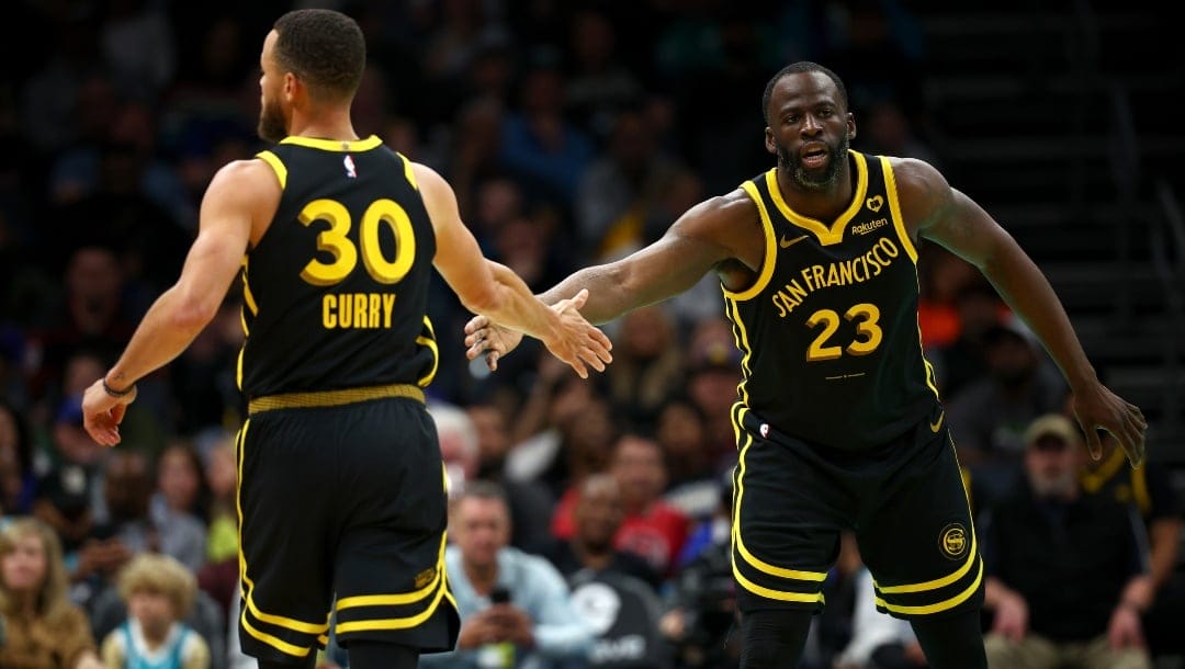 Draymond Green #23 and Stephen Curry #30 of the Golden State Warriors react during the first half of the game against the Charlotte Hornets at Spectrum Center on March 29, 2024 in Charlotte, North Carolina.