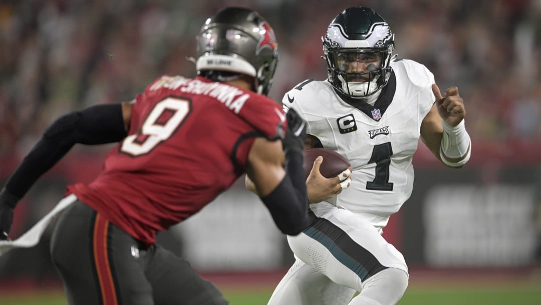 Philadelphia Eagles quarterback Jalen Hurts (1) scrambles for yardage in front of Tampa Bay Buccaneers linebacker Joe Tryon-Shoyinka (9) during the first half of an NFL wild-card playoff football game, Monday, Jan. 15, 2024, in Tampa, Fla.