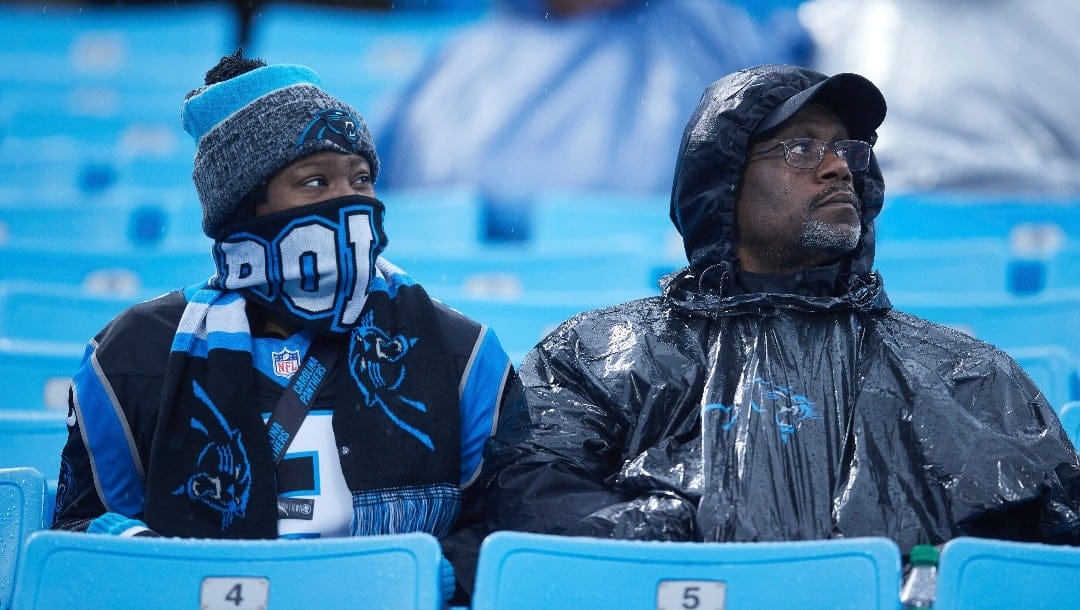 A pair of Carolina Panthers fans brave the rain to support their team prior to an NFL football game against the Atlanta Falcons, Sunday, Dec. 17, 2023, in Charlotte, N.C. (AP Photo/Brian Westerholt)