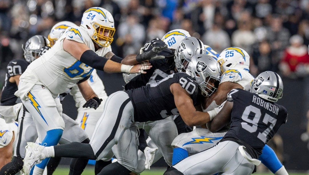 Las Vegas Raiders defensive tackle Jerry Tillery (90) tackles Los Angeles Chargers running back Joshua Kelley (25) in an NFL football game, Thursday, Dec. 14, 2023, in Las Vegas, NV. Raiders defeat the Chargers 63-21. (AP Photo/Jeff Lewis)