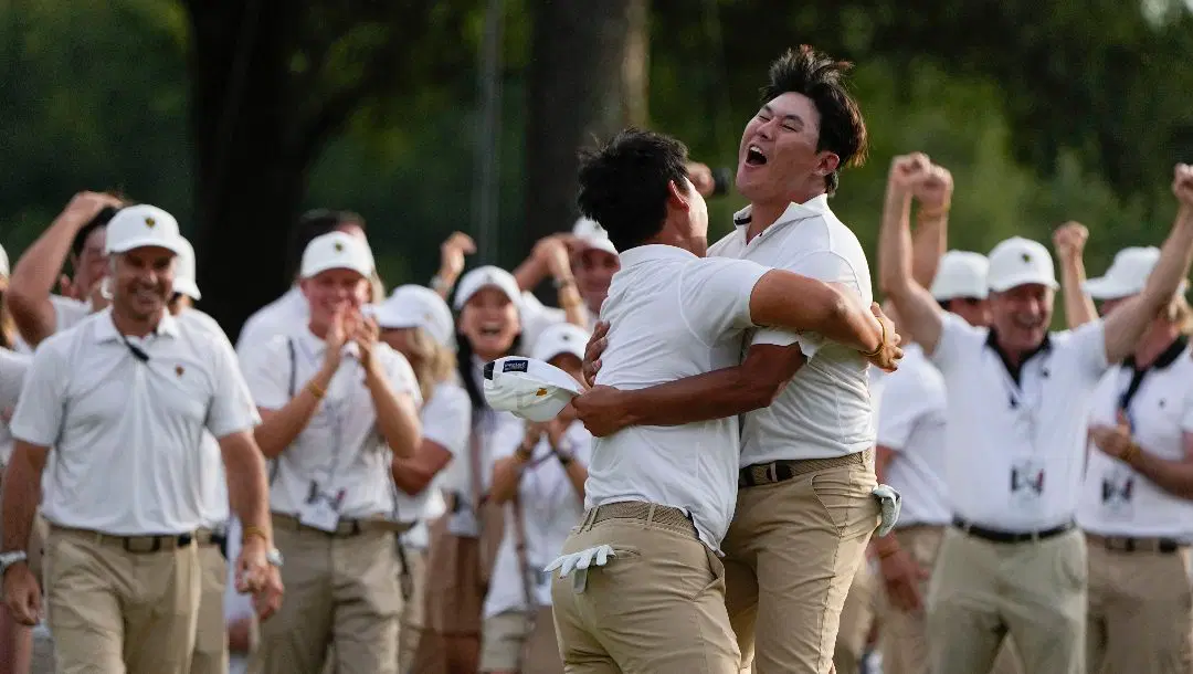 Tom Kim, of South Korea, left embraces teammate Si Woo Kim, of South Korea, after they won on the 18th hole during their fourball match at the Presidents Cup golf tournament at the Quail Hollow Club, Saturday, Sept. 24, 2022, in Charlotte, N.C.