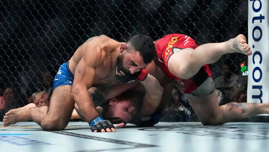 Benoit Saint Denis, of France, works against Matt Frevola, right, during the first round of a lightweight bout at the UFC 295.