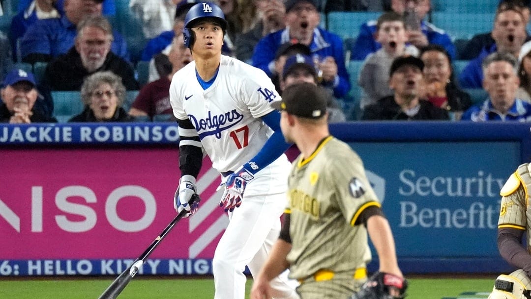 Los Angeles Dodgers' Shohei Ohtani, left, heads to first after hitting a solo home run as San Diego Padres pitcher Michael King watches during the first inning of a baseball game Friday, April 12, 2024, in Los Angeles.