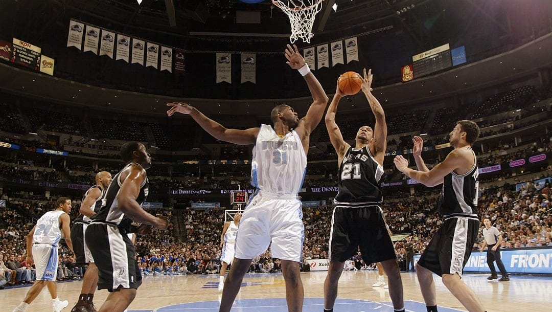 Tim Duncan #21 of the San Antonio Spurs pulls down a defensive rebound against Nene #31 of the Denver Nuggets in the first half January 5, 2003 at the Pepsi Center in Denver, Colorado. Duncan had 30 points, 12 rebounds and seven assists in the Spurs 98-74 win.