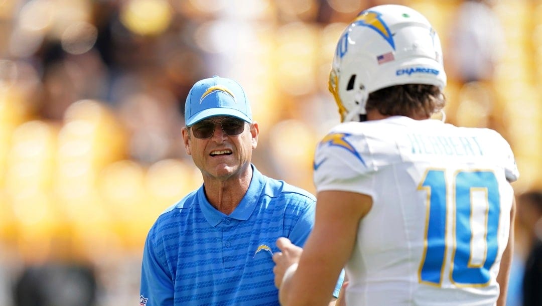 Los Angeles Chargers head coach Jim Harbaugh, left, tosses a ball to quarterback Justin Herbert before an NFL football game against the Pittsburgh Steelers, Sunday in Pittsburgh, Sept. 22, 2024. (AP Photo/Matt Freed)