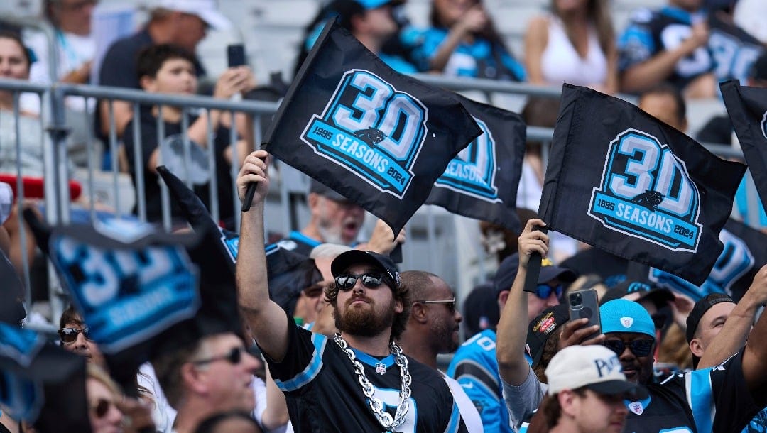 Carolina Panthers fans hold flags commemorating the 30th anniversary of the franchise prior to an NFL Football game against the Los Angeles Chargers, Sunday, Sep. 15, 2024, in Charlotte, N.C. The Chargers defeated the Panthers 26-3. (AP Photo/Brian Westerholt)