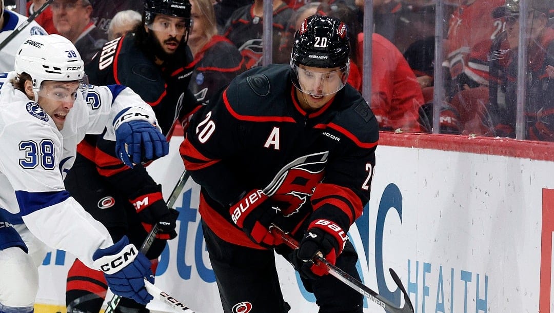 Carolina Hurricanes' Sebastian Aho (20) and Tampa Bay Lightning's Brandon Hagel (38) battle for the puck during the first period of an NHL hockey game in Raleigh, N.C., Friday, Oct. 11, 2024. (AP Photo/Karl B DeBlaker)