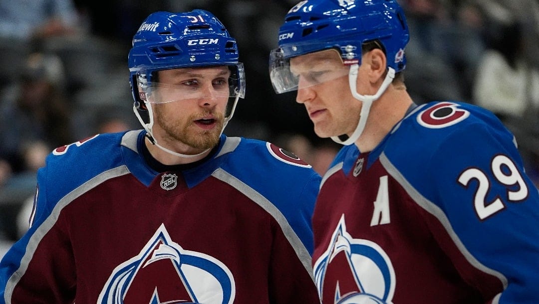 Colorado Avalanche right wing Nikolai Kovalenko, left, confers with center Nathan MacKinnon in the second period of an NHL preseason hockey game against the Vegas Golden Knights, Tuesday, Oct. 1, 2024, in Denver. (AP Photo/David Zalubowski)