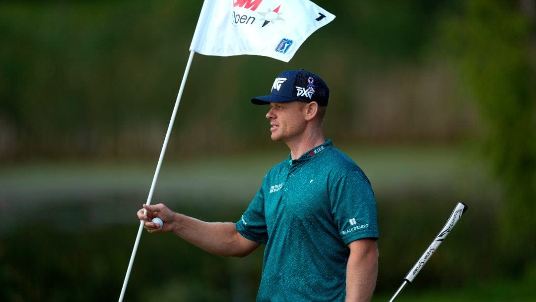 Patrick Fishburn holds the flag on the first green during the second round of the 3M Open golf tournament at the Tournament Players Club, Friday, July 26, 2024, in Blaine, Minn.