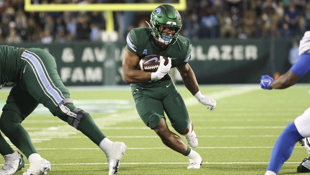 Tulane running back Makhi Hughes, center, runs yardage during the first half of an NCAA college football game against Memphis in New Orleans, Thursday, Nov. 28, 2024.