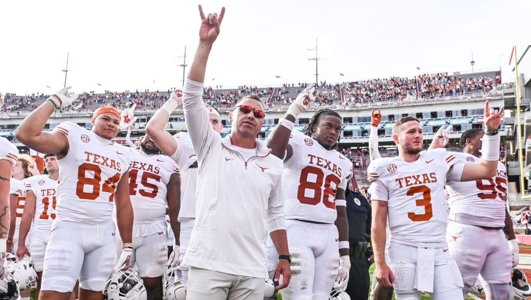 Texas tight end Jordan Washington (84), coach Steve Sarkisian, defensive back Barryn Sorrell (88) and quarterback Quinn Ewers (3) celebrate with their team after defeating Arkansas 20-10 during an NCAA college football game Saturday, Nov. 16, 2024, in Fayetteville, Ark.