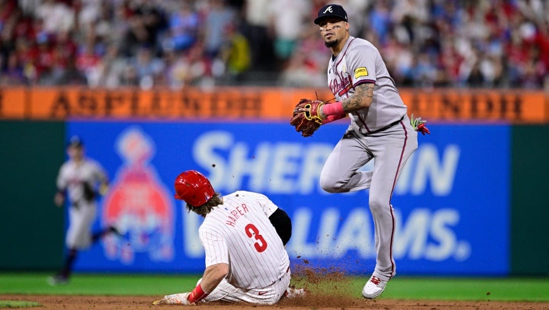 Atlanta Braves' Orlando Arcia, right, leaps after a force out against Philadelphia Phillies' Bryce Harper (3) during the ninth inning of a baseball game, Sunday, Sept. 1, 2024, in Philadelphia.