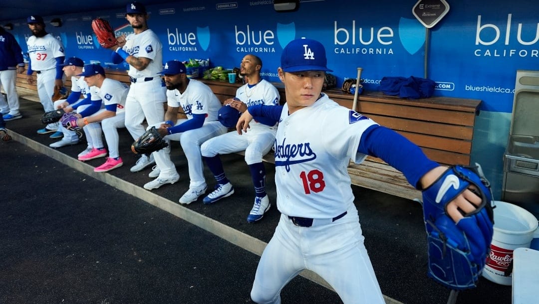 Los Angeles Dodgers starting pitcher Yoshinobu Yamamoto (18) warms up in the dugout before a baseball game against the Colorado Rockies in Los Angeles, Saturday, June 1, 2024.