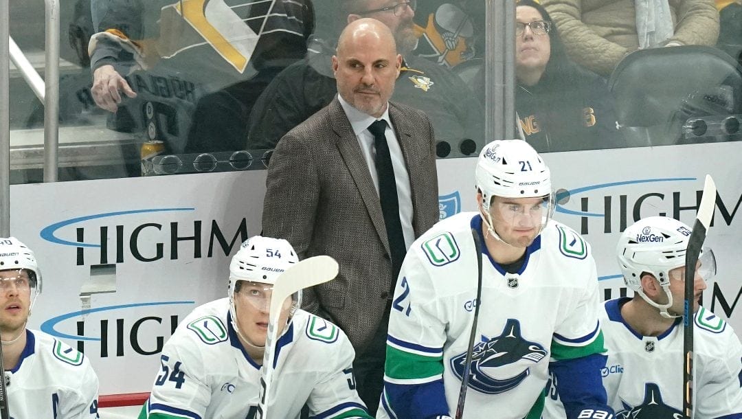 Vancouver Canucks head coach Rick Tocchet stands behind his bench during the first period of an NHL hockey game against the Pittsburgh Penguins Wednesday, Nov. 27, 2024, in Pittsburgh.