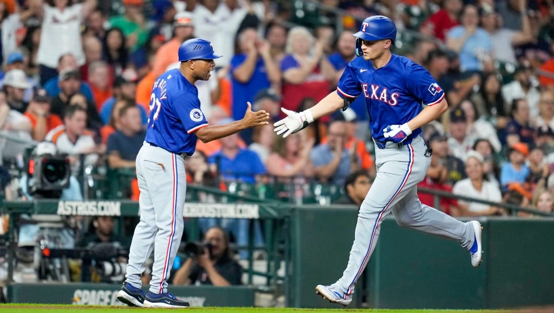 Texas Rangers' Corey Seager, right, celebrates after his two-run home run with third base coach Tony Beasley during the sixth inning of a baseball game against the Houston Astros, Friday, July 12, 2024, in Houston.