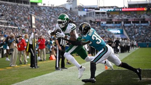 New York Jets wide receiver Davante Adams (17) catches a 1-yard touchdown pass as Jacksonville Jaguars cornerback Montaric Brown (30) defends during the second half of an NFL football game, Sunday, Dec. 15, 2024, in Jacksonville, Fla.