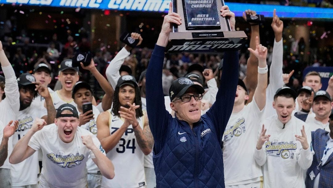 Akron head coach John Groce, center, holds the trophy after the team defeated Miami (Ohio) in an NCAA college basketball game in the championship of the Mid-American Conference tournament, Saturday, March 15, 2025, in Cleveland, Ohio.