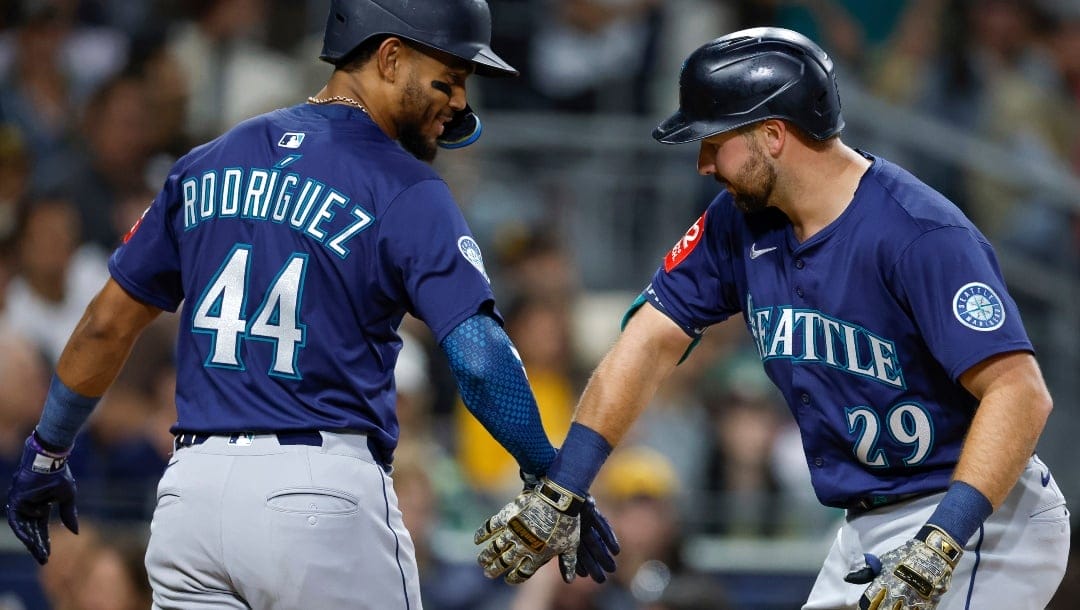 Seattle Mariners' Cal Raleigh, right, is greeted by Julio Rodriguez, left, after hitting a two-run home run during the sixth inning of a baseball game against the San Diego Padres, Friday, May 16, 2025, in San Diego.