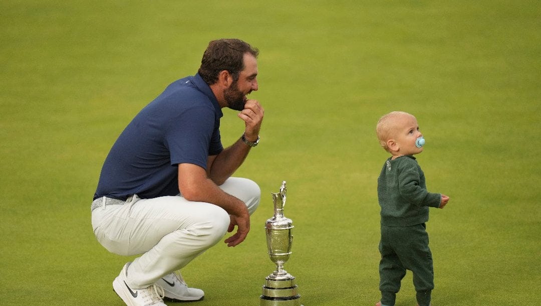 Scottie Scheffler of the United States holds the Claret Jug trophy as his son Bennett stands on the 18th green after winning the British Open golf championship at the Royal Portrush Golf Club, Northern Ireland, Sunday, July 20, 2025.